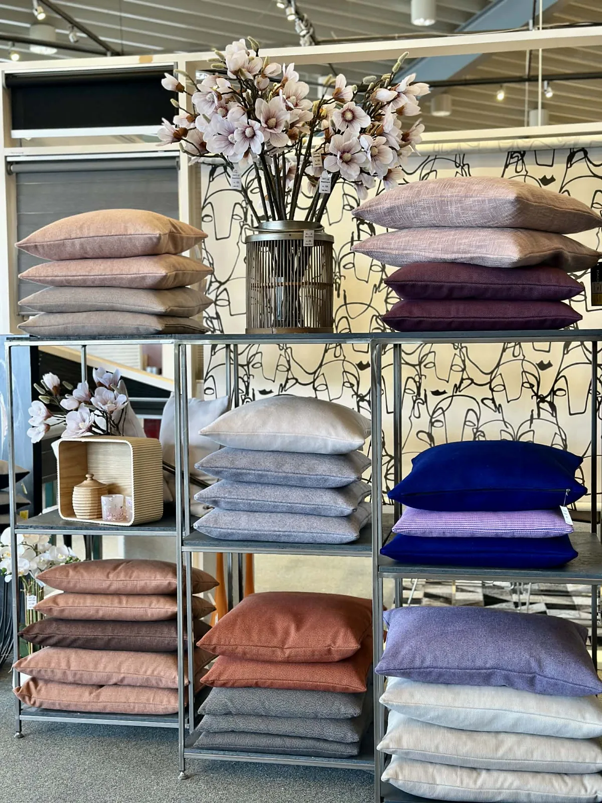 Reol med puder i lilla, rosa og støvede nuancer i showroomet i Holbæk
